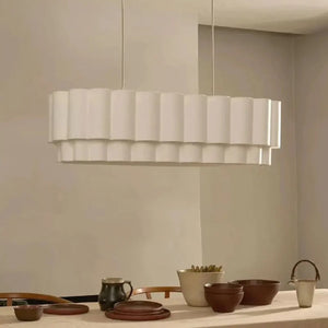 Suspension linéaire en tissu beige éclairée au-dessus d'une table dressée avec vaisselle artisanale