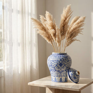 Vase chinois ouvert avec pampas séchées près d'une fenêtre voilée