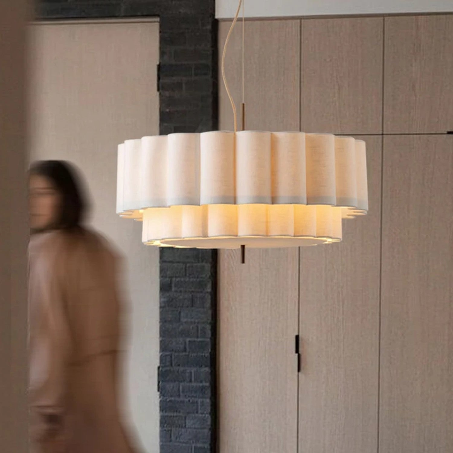Suspension ronde en tissu beige allumée diffusant une lumière chaude dans un intérieur contemporain