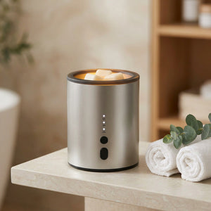 Brûle-parfum électrique argenté sur une étagère de salle de bain avec serviettes et eucalyptus