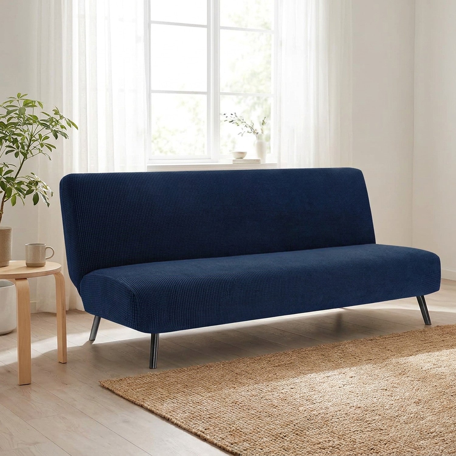 Housse de canapé convertible bleu marine sur une banquette près d'une fenêtre lumineuse