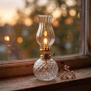 Lampe à huile vintage allumée sur un rebord de fenêtre au coucher du soleil