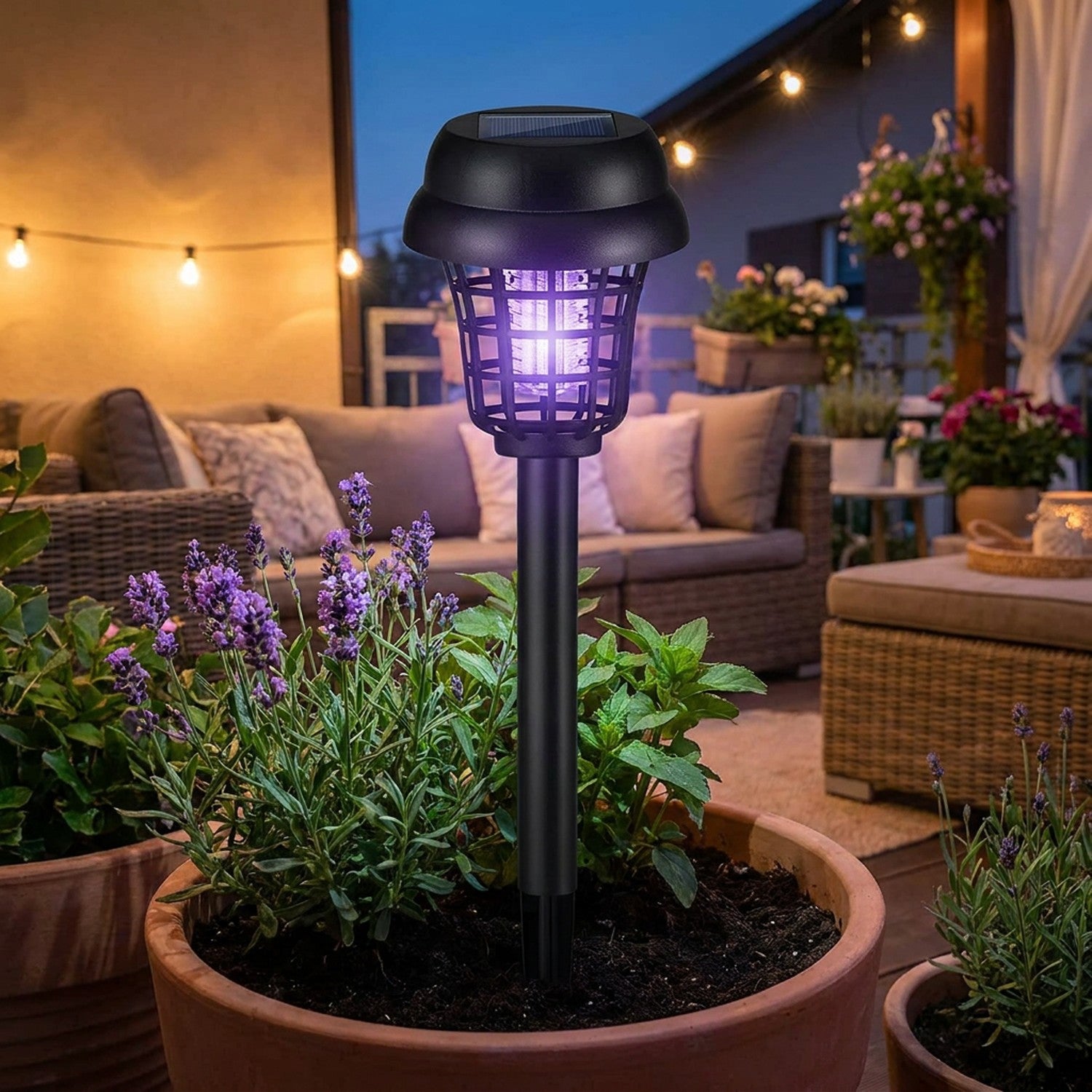 Lampe solaire anti-moustiques plantée dans un pot sur une terrasse cosy en soirée