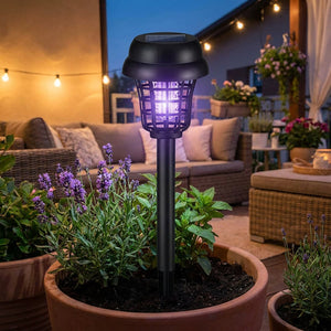 Lampe solaire anti-moustiques plantée dans un pot sur une terrasse cosy en soirée