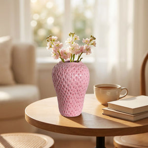 Vase rose en forme de fraise sur une table bistro près d'une fenêtre avec une tasse de thé