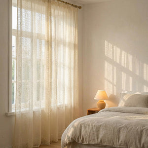 Voilage beige à motif losange dans une chambre lumineuse avec lit en lin et lampe de chevet