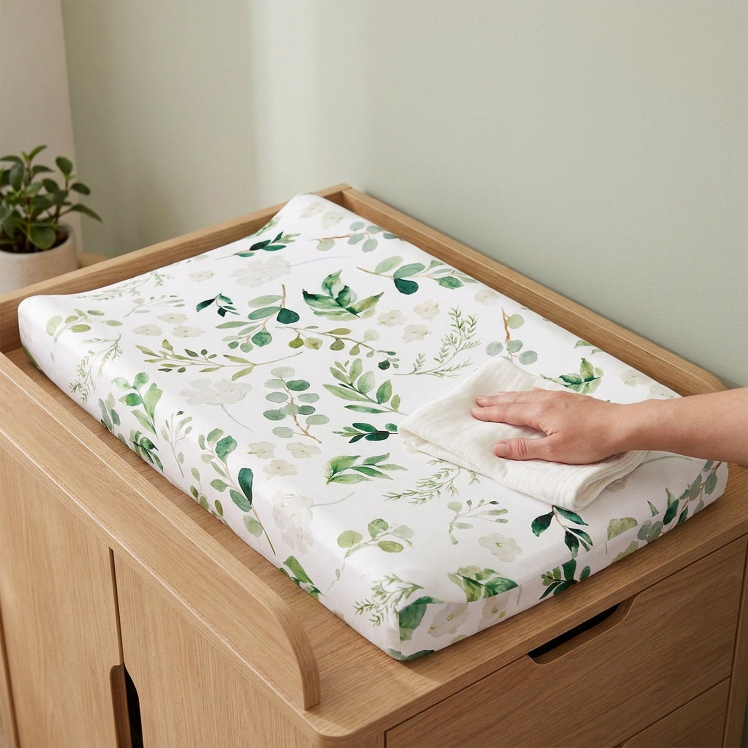 Housse de matelas à langer motif feuillage avec un linge de change posé à côté