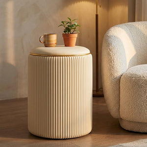 Tabouret de rangement beige utilisé comme table d'appoint près d'un fauteuil