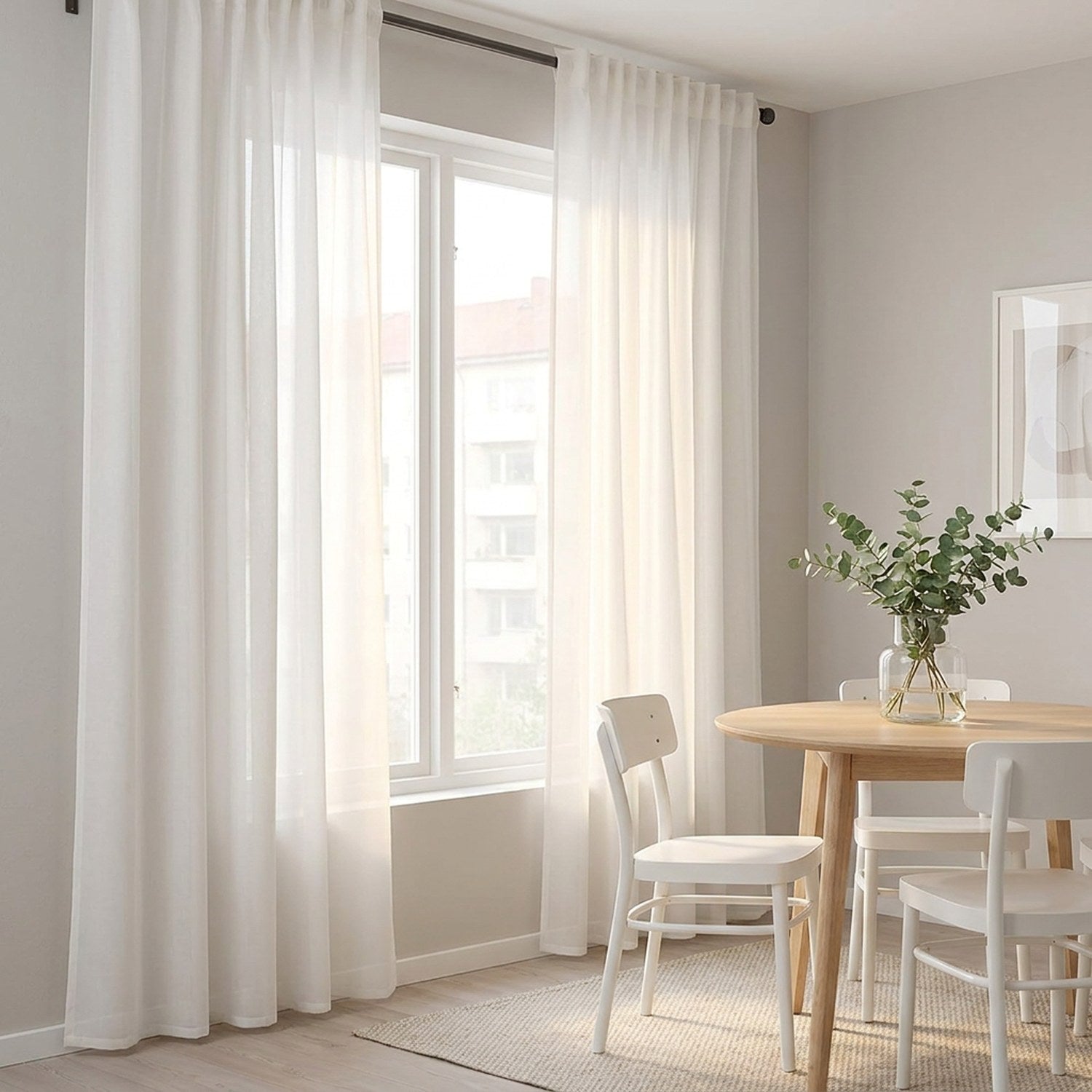 Voilage blanc en tulle transparent habillant une fenêtre dans un coin repas scandinave
