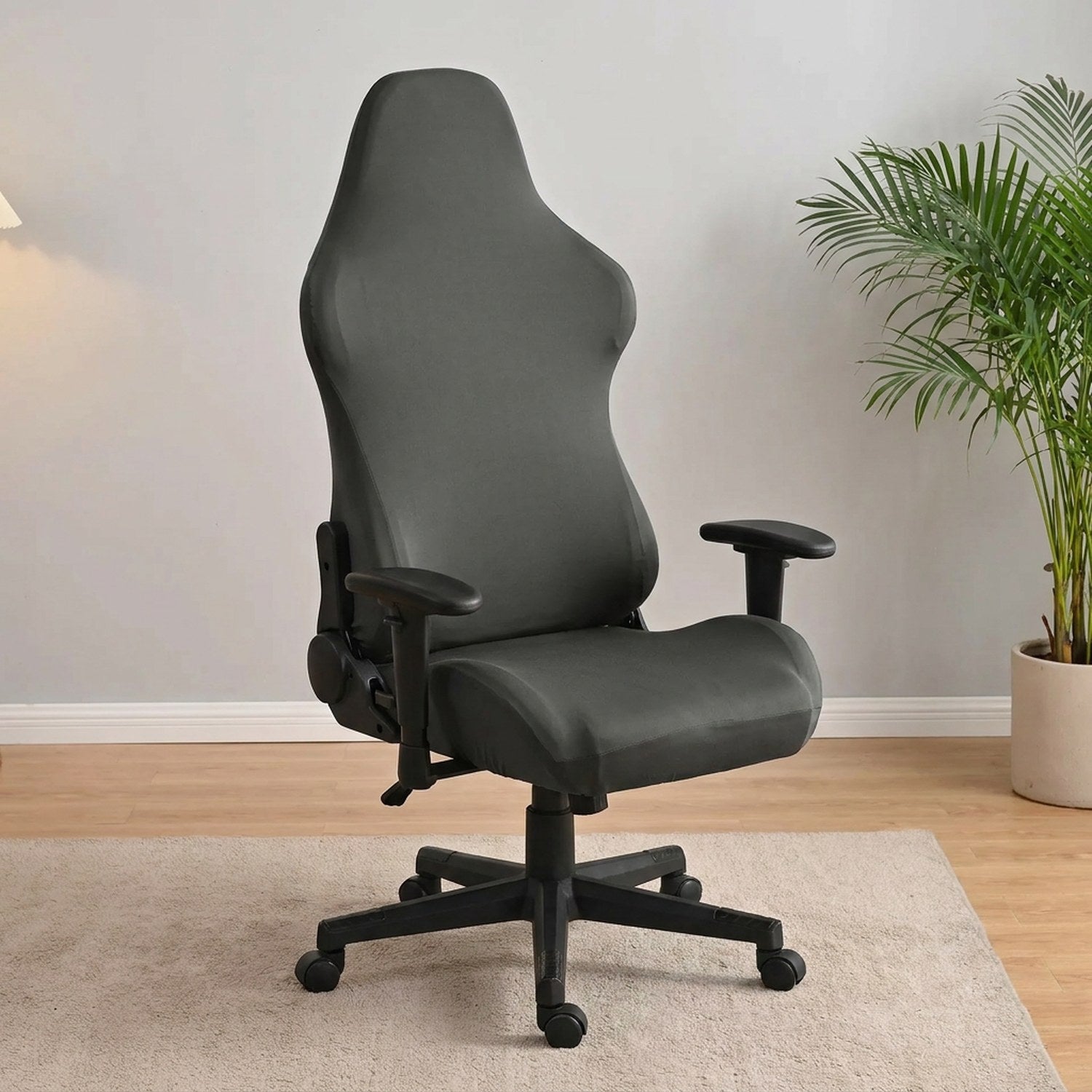 Housse de chaise gaming grise épousant le dossier baquet dans un bureau moderne