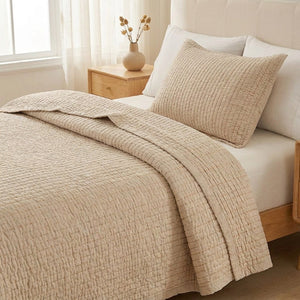 Gros plan sur le couvre-lit matelassé beige plié révélant les fines lignes en relief