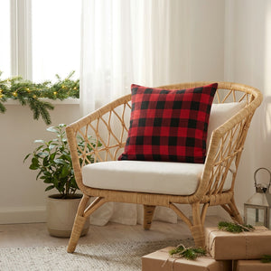 Housse de coussin de Noël à carreaux sur un fauteuil en rotin près d'une fenêtre