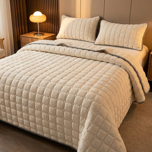 Couvre-lit matelassé velours écru sur un lit avec lampe de chevet chaleureuse