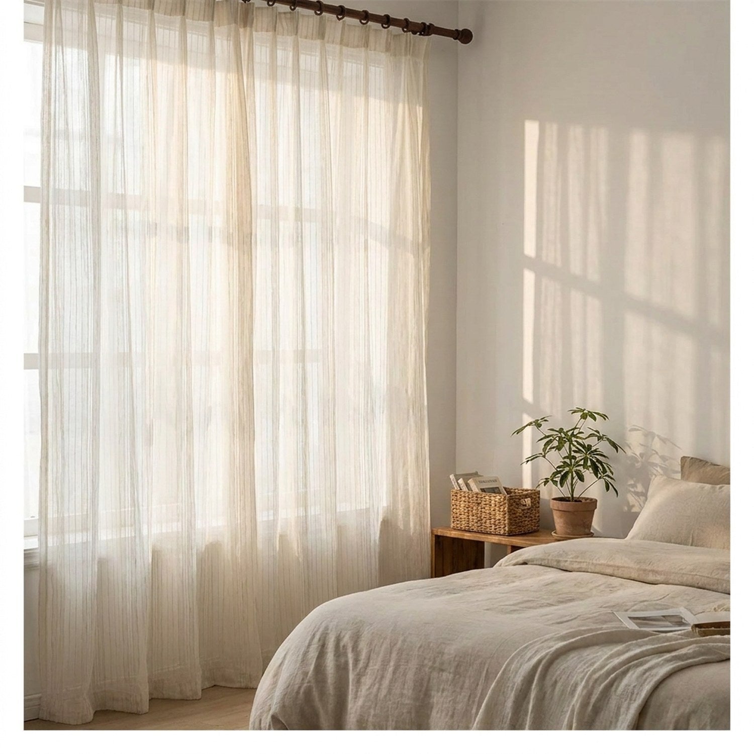 Voilage blanc rayé dans une chambre lumineuse avec lit en lin et panier en osier