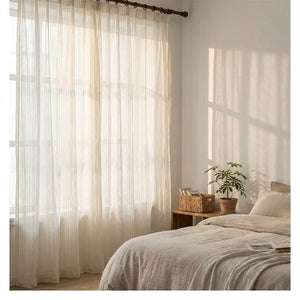 Voilage blanc rayé dans une chambre lumineuse avec lit en lin et panier en osier