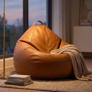 Pouf poire en simili cuir dans un coin lecture près d'une fenêtre au crépuscule