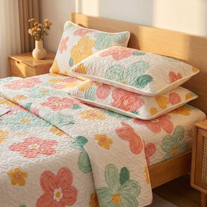 Détail des taies quilted fleuries empilées contre une tête de lit en bois