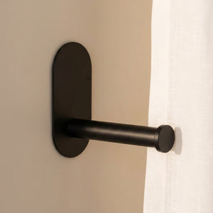 Gros plan sur l'embrasse adhésive noire et sa base ovale fixée au mur