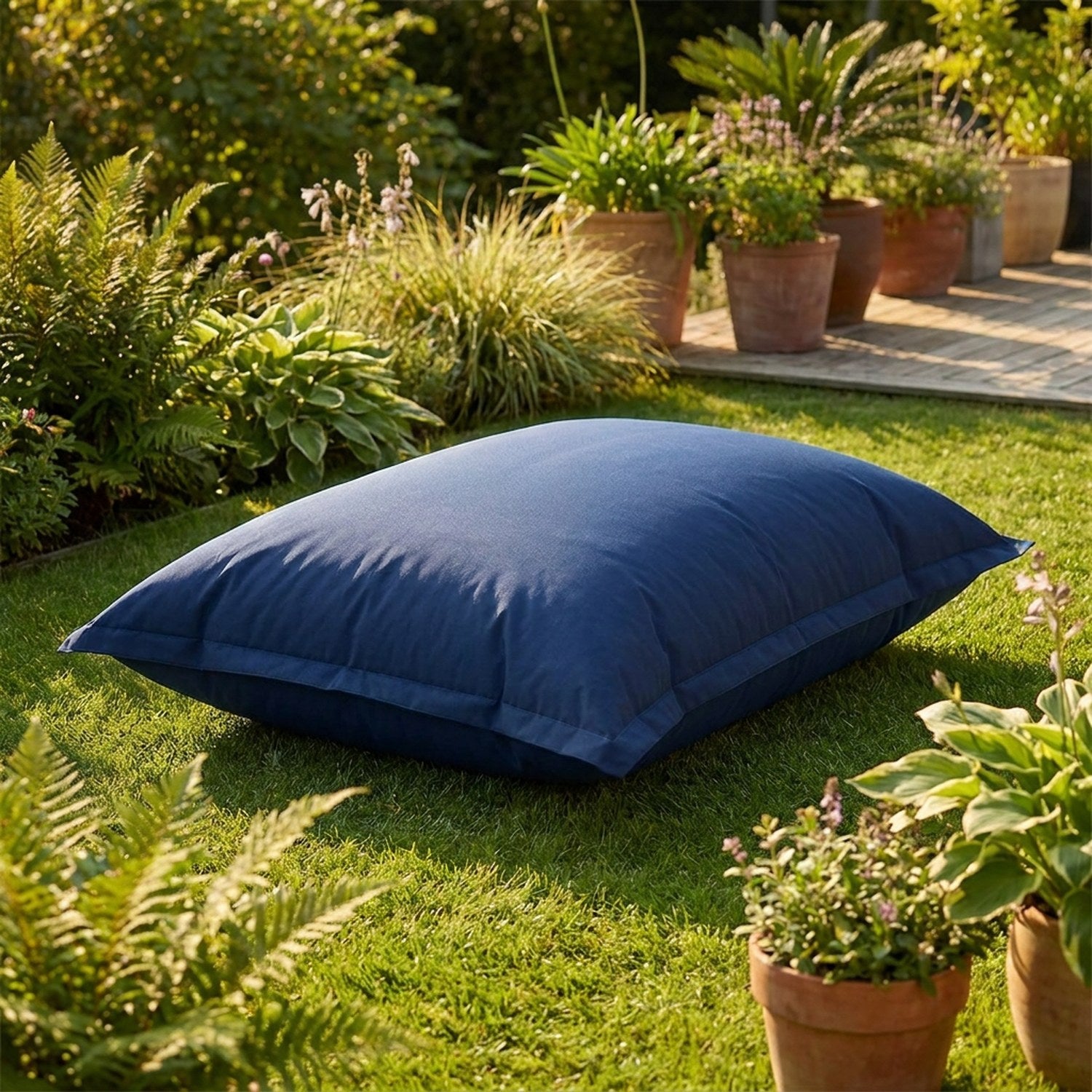 Pouf géant bleu marine posé sur une pelouse de jardin ensoleillée