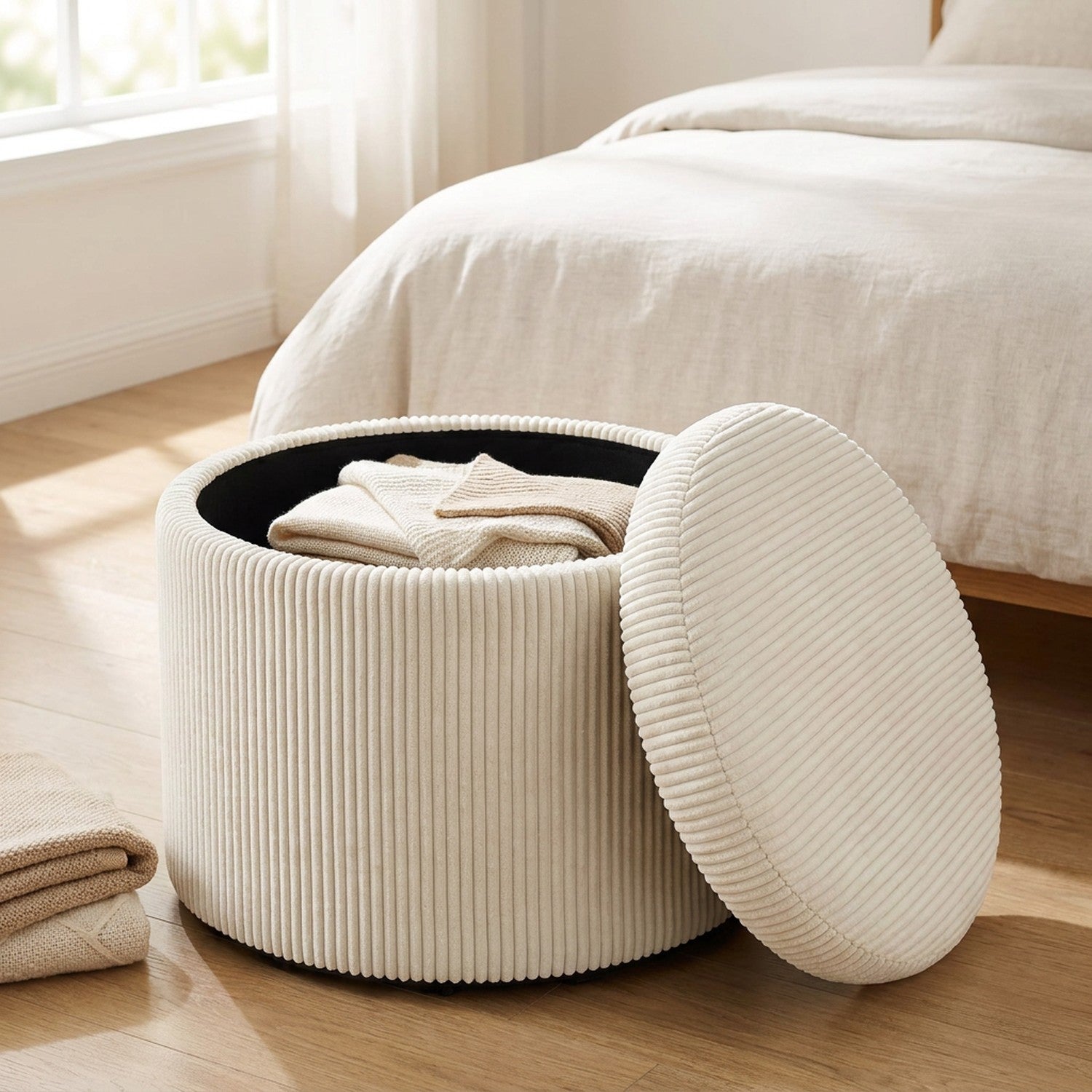 Pouf de rangement ouvert révélant le coffre intérieur rempli de plaids