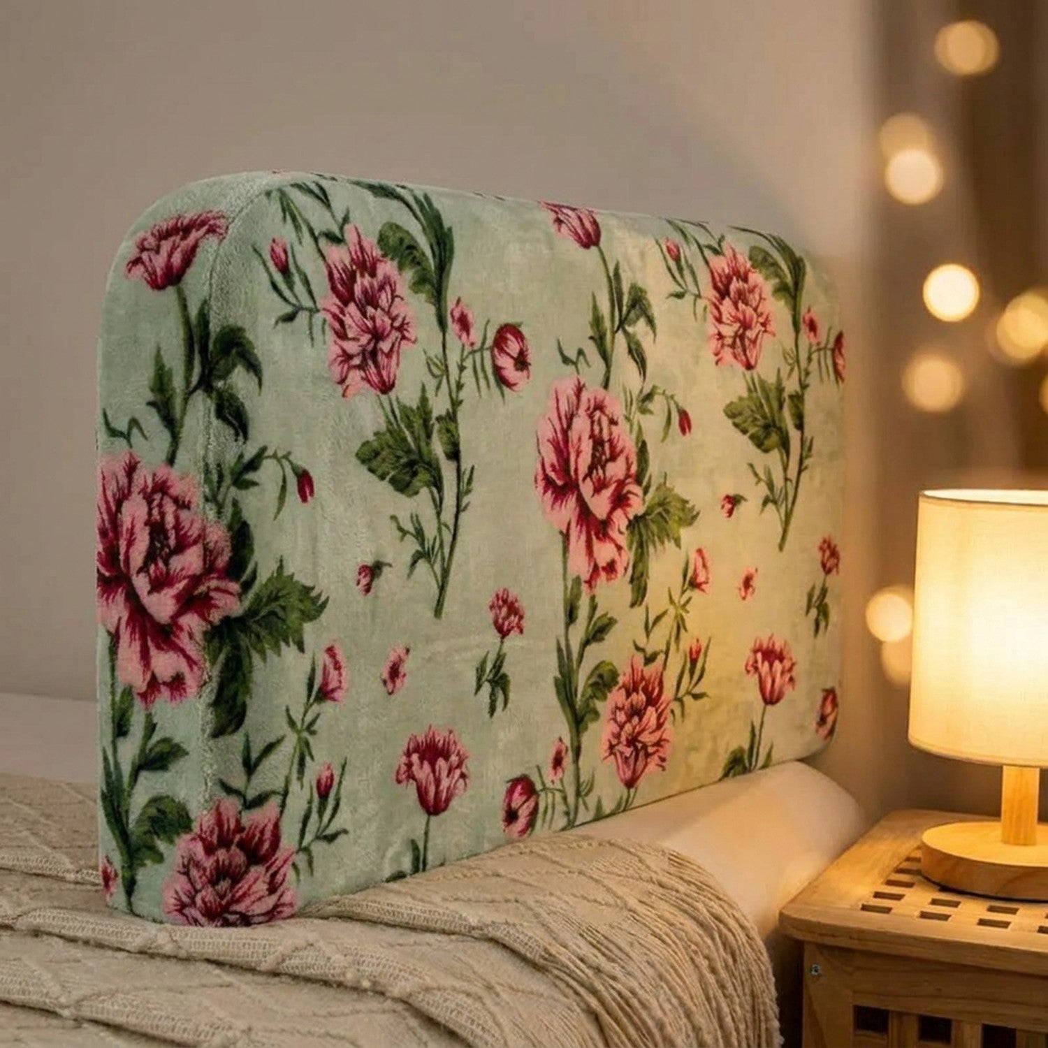 Gros plan sur le velours doux d'une housse de tête de lit à motif de roses éclairée par une lampe chaude
