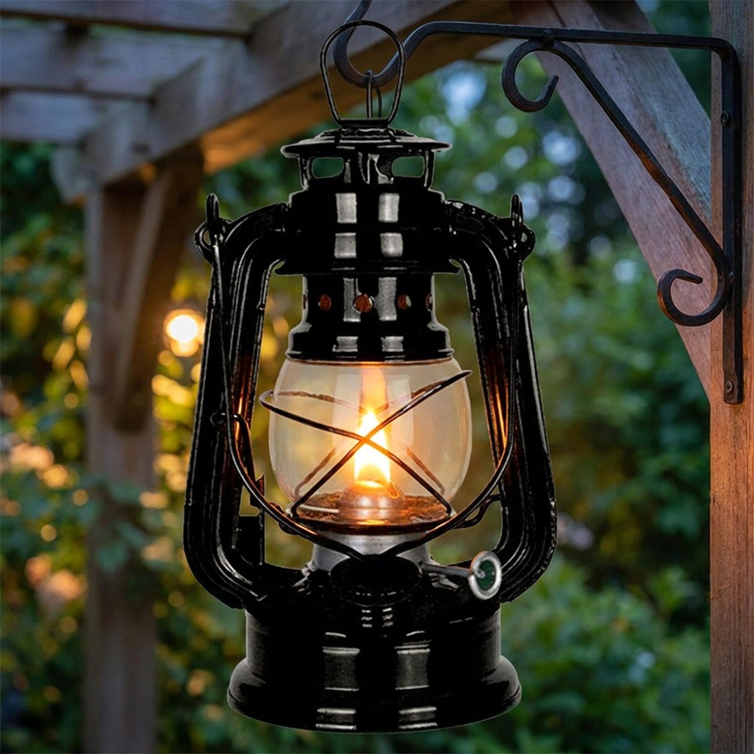 Lanterne à pétrole suspendue à un crochet en fer dans un jardin verdoyant au crépuscule