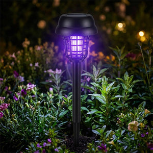 Gros plan d'une lampe anti moustique solaire à lumière violette dans un massif de fleurs la nuit