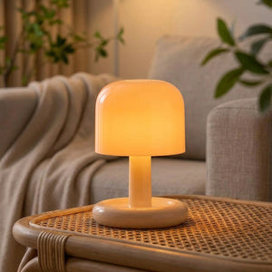 Lampe champignon posée sur une table en rotin à côté d'un canapé et d'un plaid