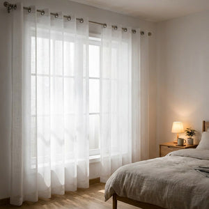 Voilage en tulle blanc à œillets dans une chambre avec lit et lampe de chevet chaleureuse