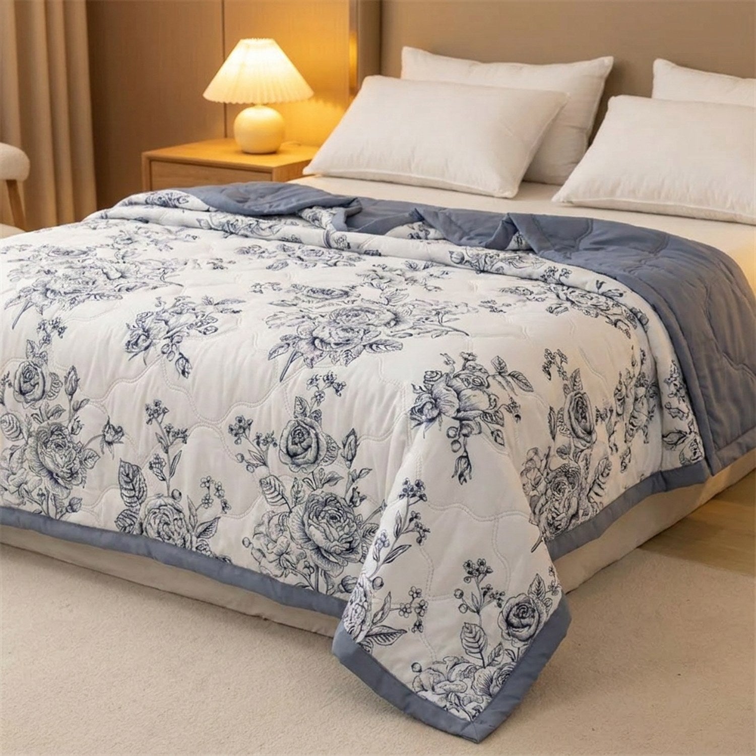 Couette d'été à roses bleutées sur un lit avec lampe de chevet chaleureuse le soir