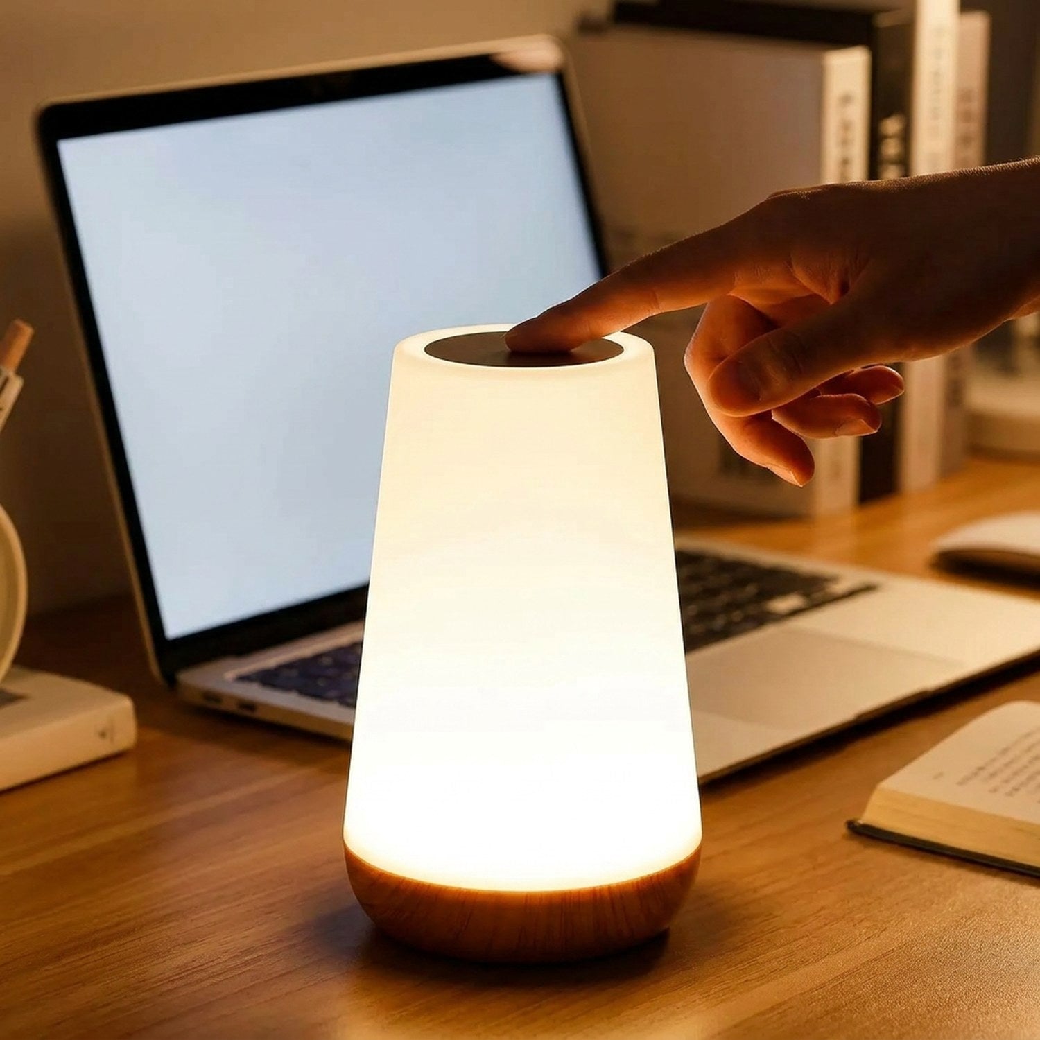 Main effleurant la zone tactile de la lampe sur un bureau le soir
