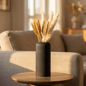 Vase noir à rainures avec pampa et blé séché sur une table d'appoint