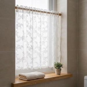 Rideau en dentelle fleurie sur une fenêtre de salle de bain