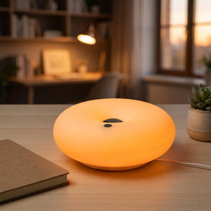 Lampe beignet Bauhaus allumée en orange sur un bureau