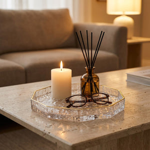 Plateau en verre à facettes avec bougie et diffuseur sur une table basse en pierre