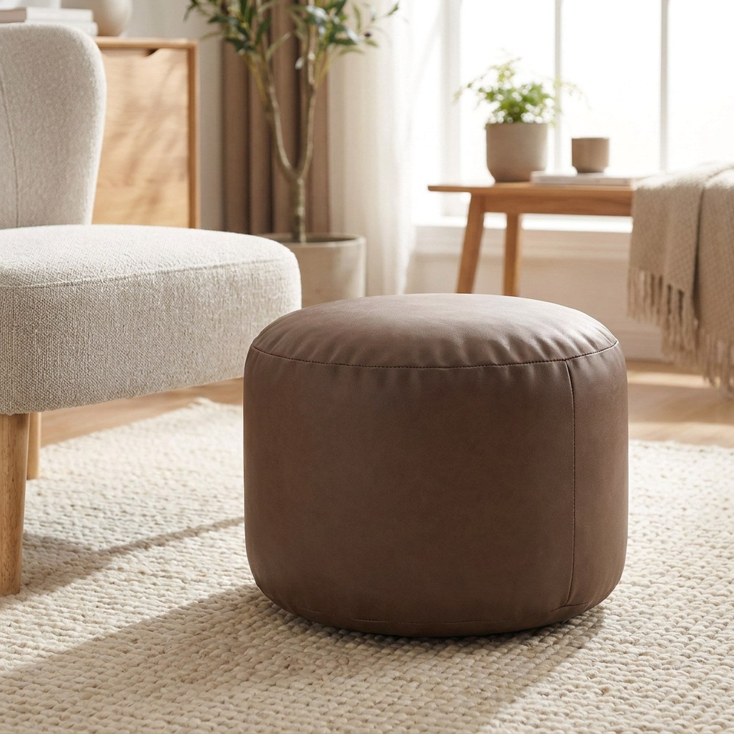 Pouf ottoman rond en simili cuir marron café en assise d appoint près d un fauteuil