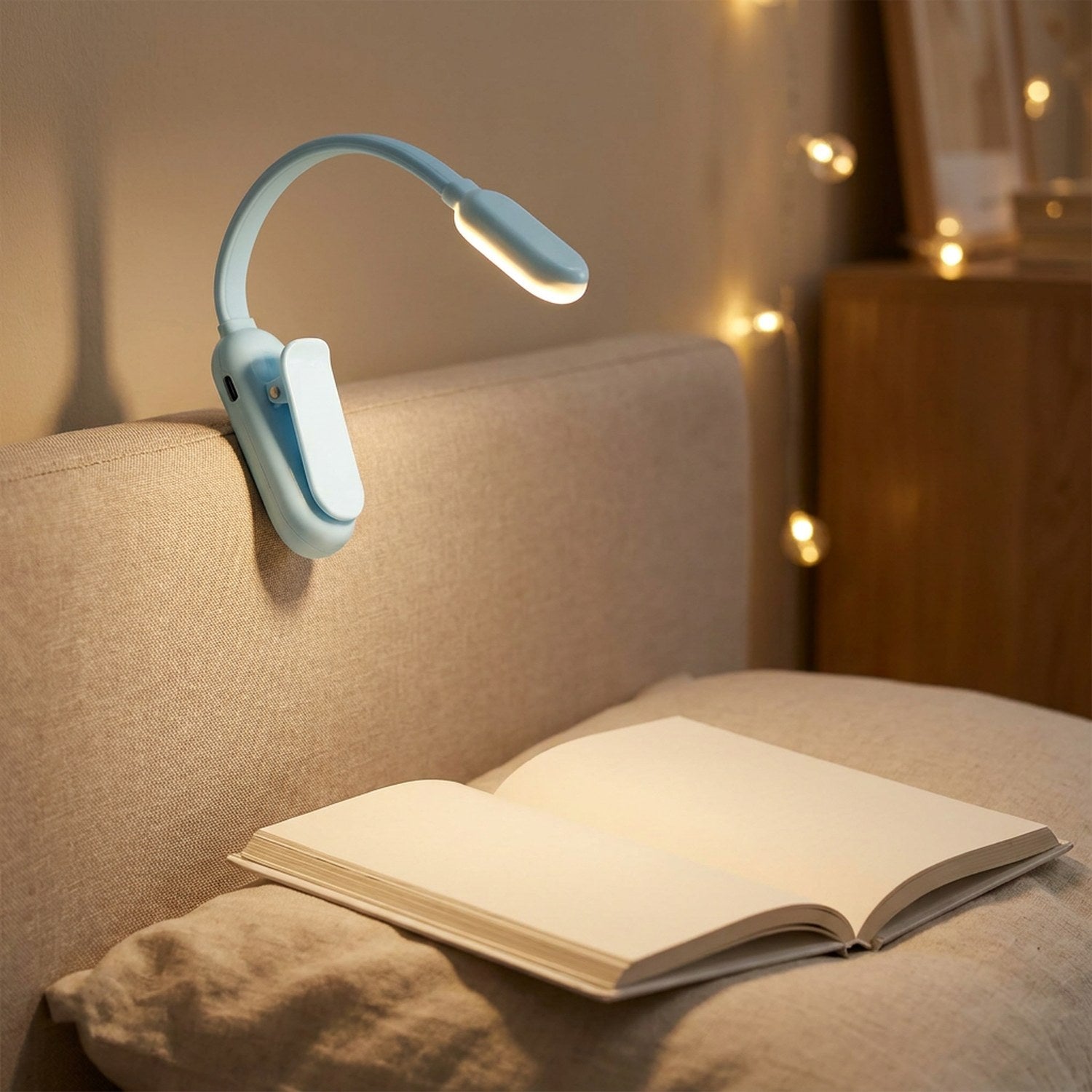 Lampe de lecture à clipser bleue fixée sur une tête de lit au-dessus d'un livre
