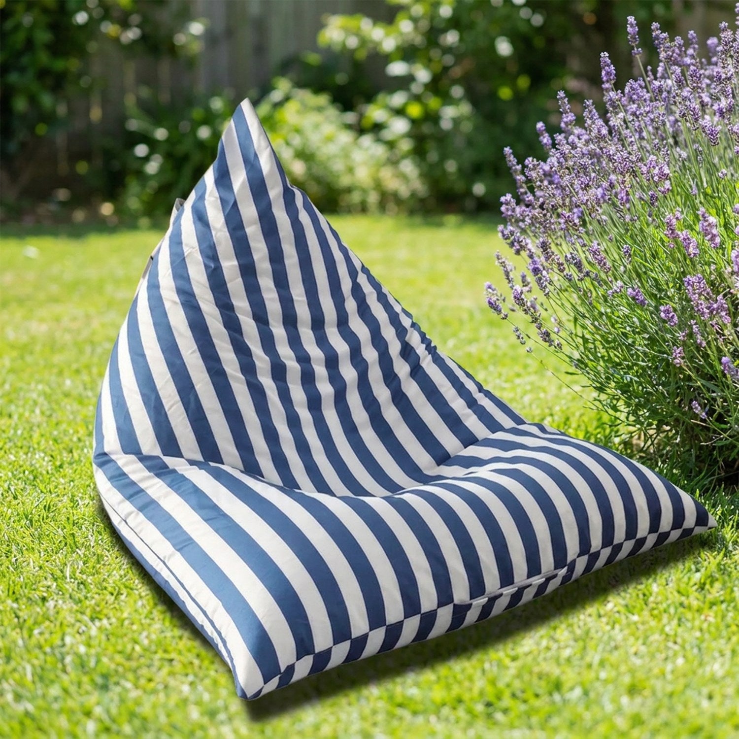 Pouf géant extérieur rayé bleu marine posé sur une pelouse de jardin