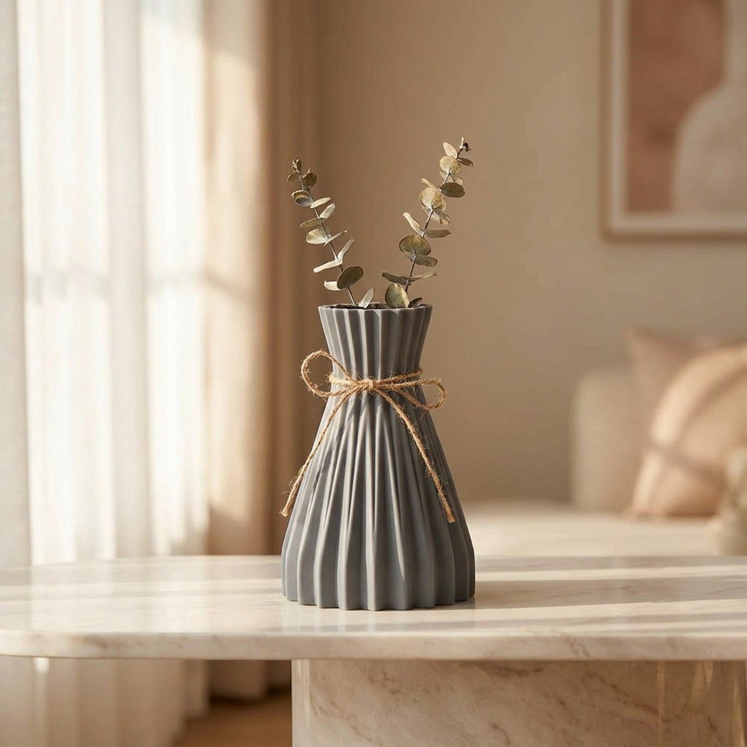Vase origami plissé gris avec de l eucalyptus sur une console en marbre