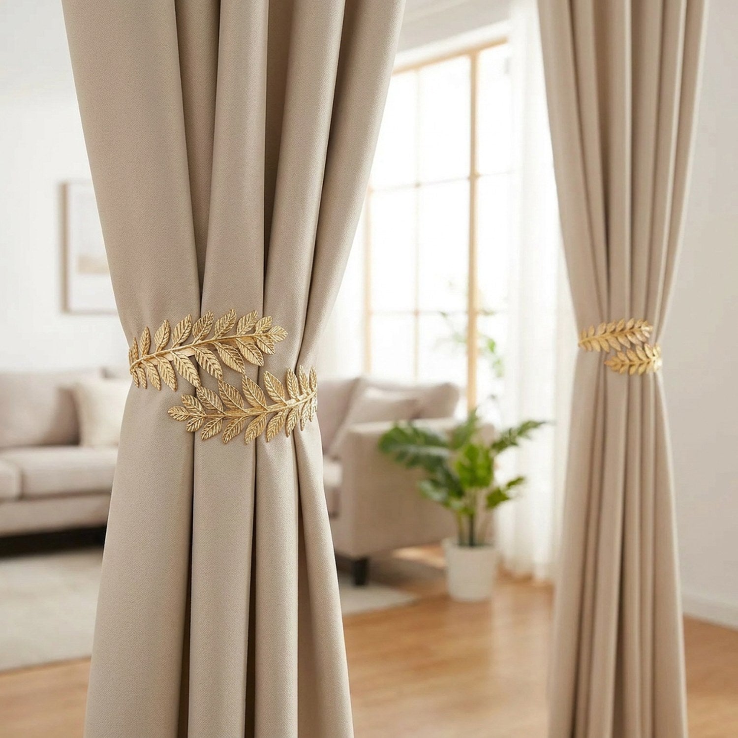 Deux embrasses dorées à feuilles retenant des rideaux beiges dans un salon lumineux