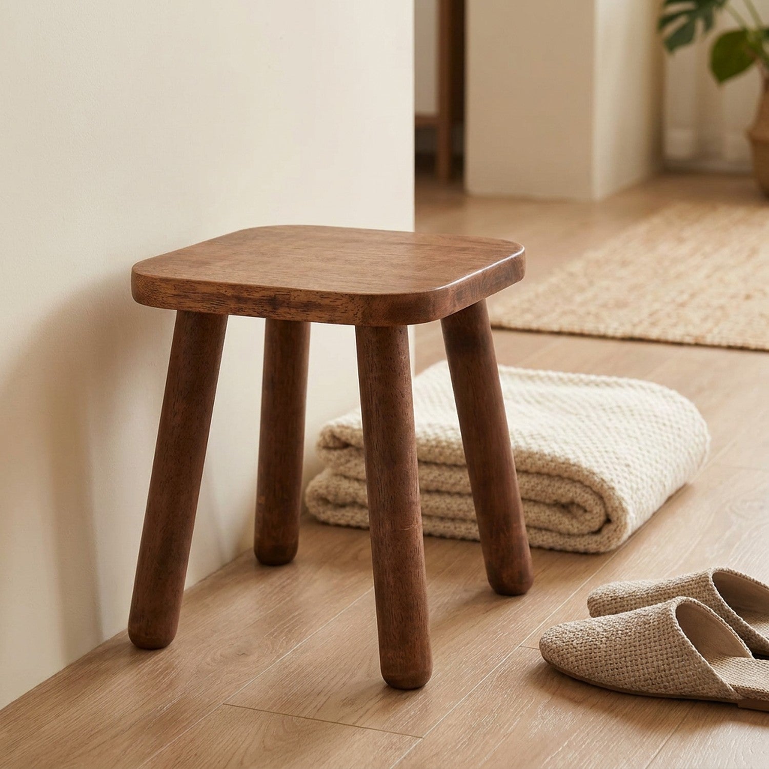 Tabouret en bois massif dans une entrée avec un plaid plié et des chaussons