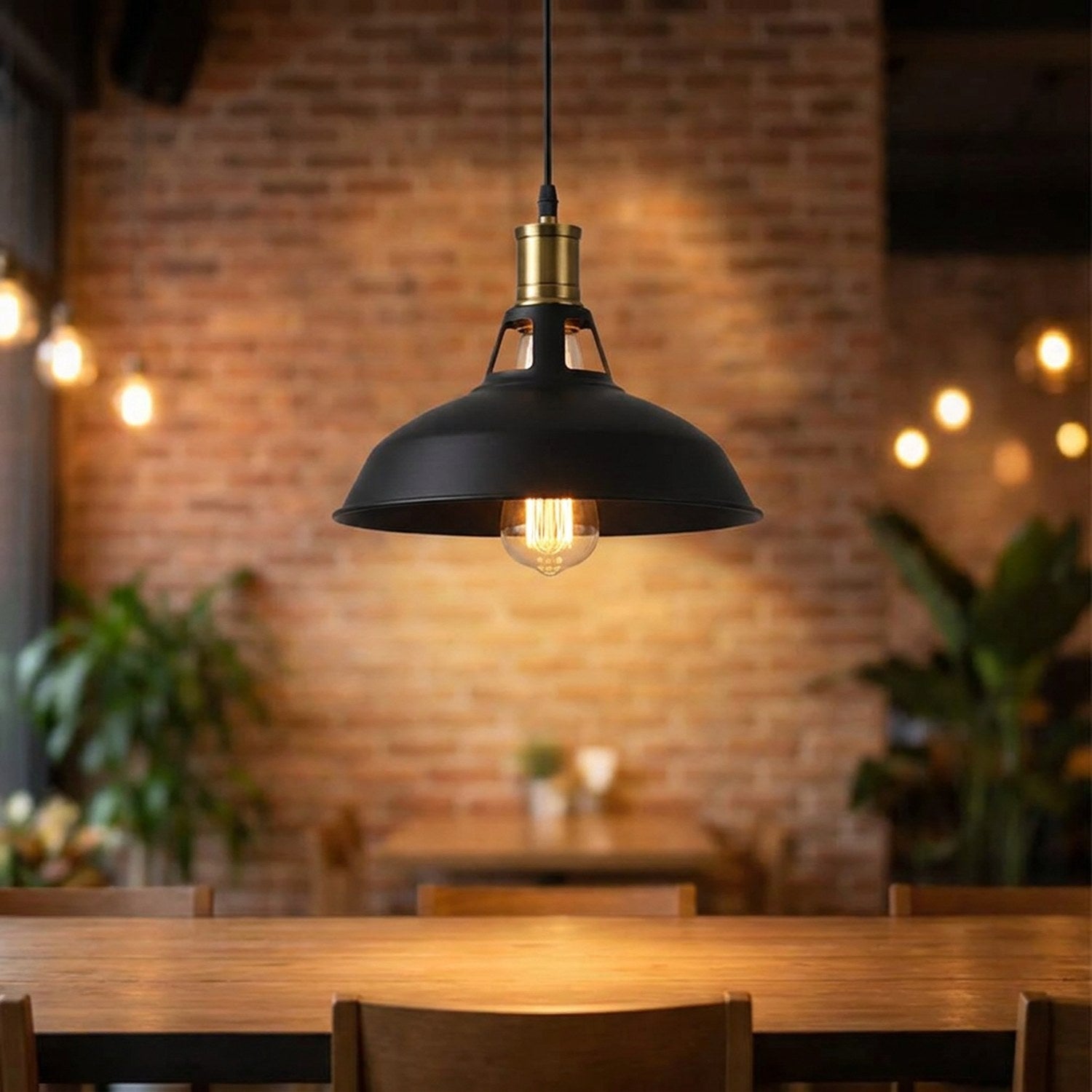 Suspension industrielle noire allumée au-dessus d'une table contre un mur de briques