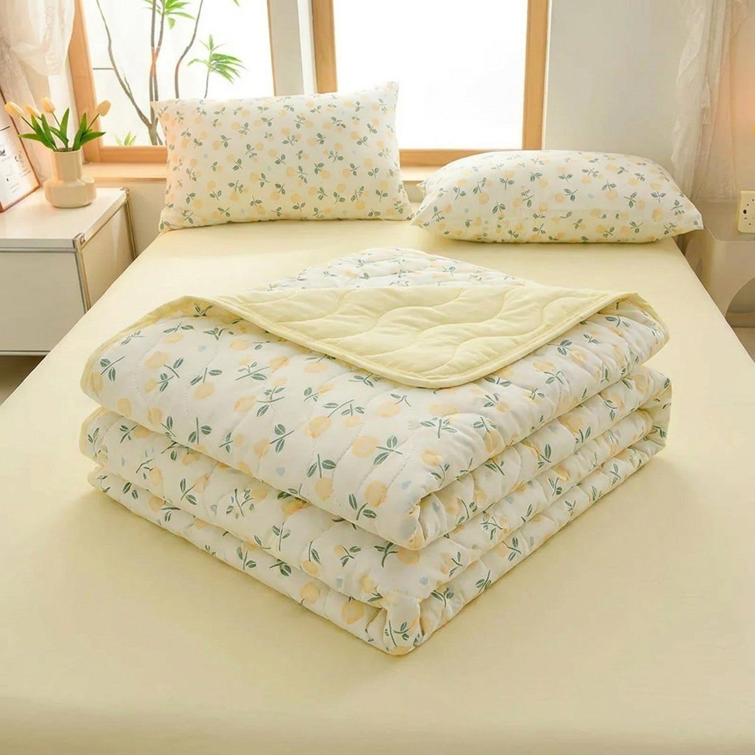 Couette à imprimé fleuri pliée sur un lit montrant l'envers uni jaune pâle