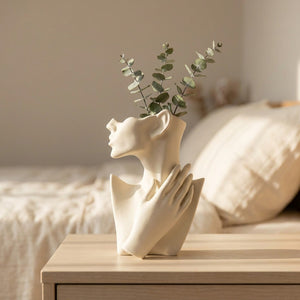 Vase visage en céramique garni d'eucalyptus sur une commode dans une chambre douce