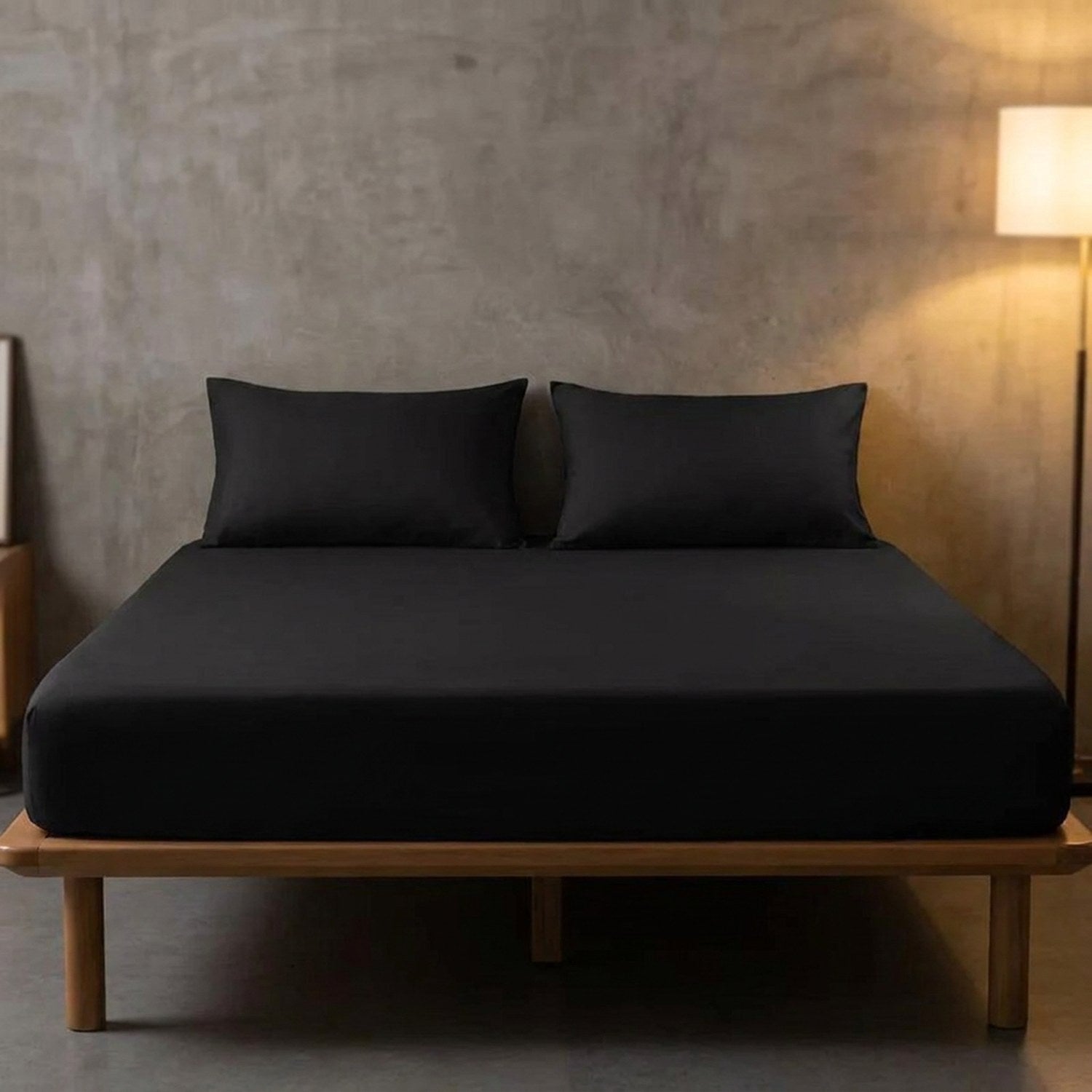 Drap housse noir sur un lit dans une chambre au mur en béton avec lampadaire