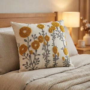 Coussin brodé fleurs moutarde sur un lit avec tête de lit en bois