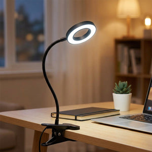 Lampe pince fixée au bord d'un bureau avec lumière blanche près d'un ordinateur portable