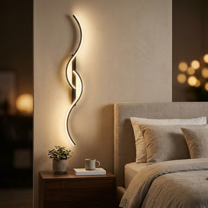 Applique murale LED noire installée en tête de lit dans une chambre cosy le soir