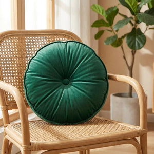Coussin rond en velours vert émeraude sur un fauteuil en rotin près d'une fenêtre