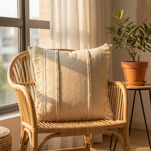 Coussin bohème beige à franges sur un fauteuil en rotin près d'une fenêtre avec une plante